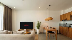 A modern living room with a flat-screen TV, a dining area, and a kitchen. - Sunny Aparts 1 by Betterplace (Tibubeneng)