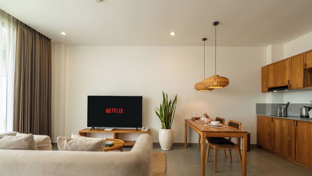 A modern living room with a flat-screen TV, a dining area, and a kitchen. - Sunny Aparts 1 by Betterplace (Tibubeneng)