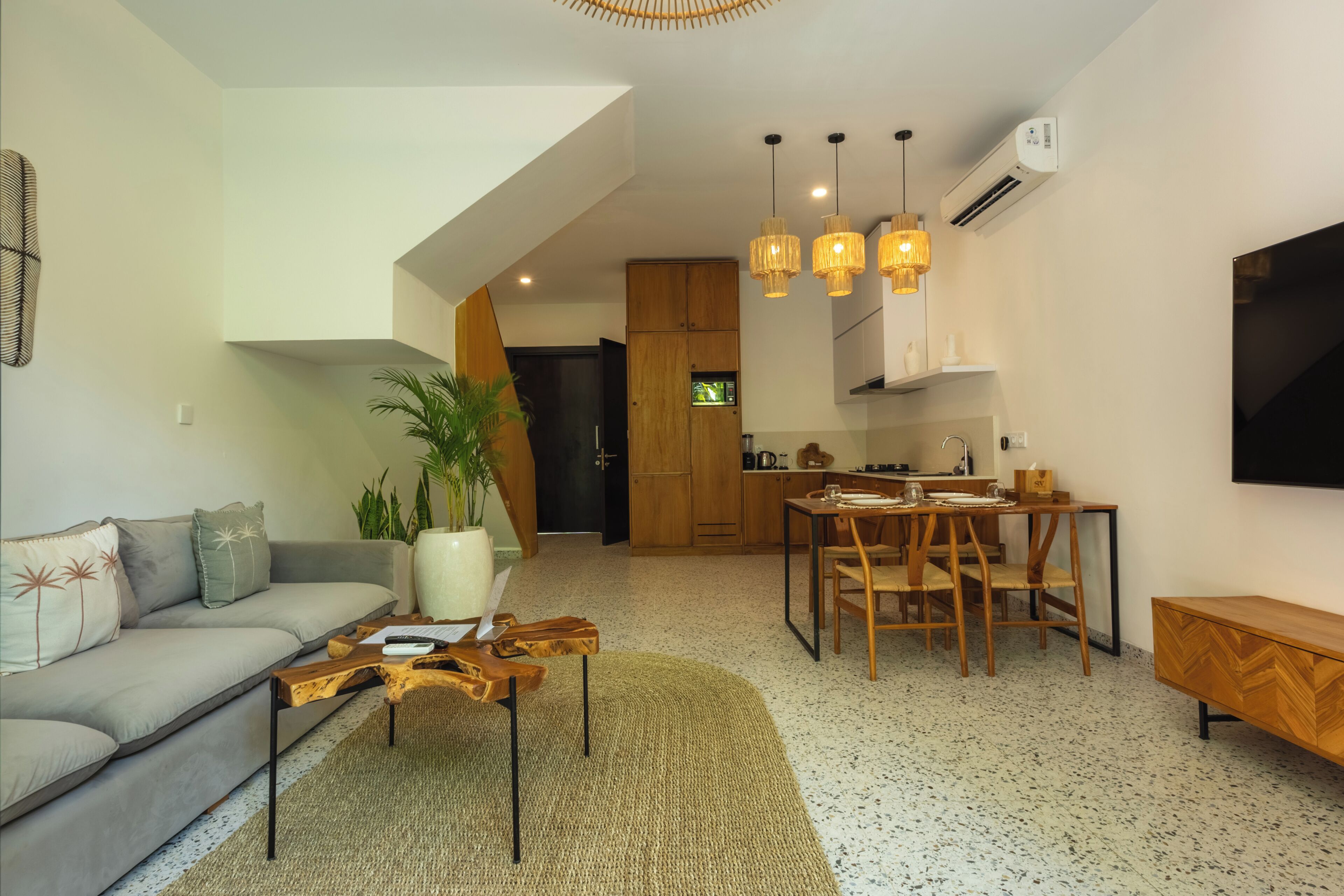 Een moderne woonkamer met een bank, salontafel en een eethoek met stoelen.
