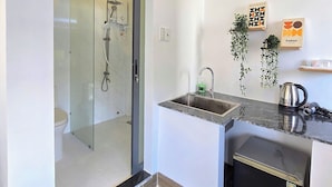 A compact bathroom with a glass shower enclosure, a sink, and a toilet. - XOAI BIEN HOMESTAY PHAN THIET GAN BIEN (Phu Thuy)
