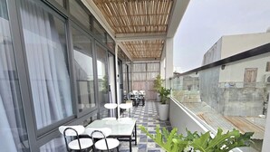 A balcony with a wooden ceiling, a dining table with chairs, and a potted plant. - XOAI BIEN HOMESTAY PHAN THIET GAN BIEN (Phu Thuy)