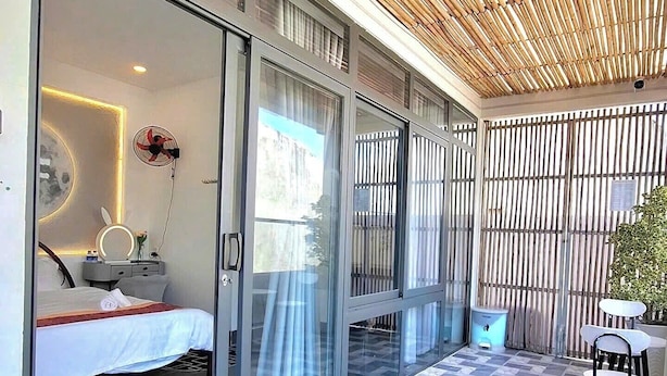 A modern hotel room with a glass door, a bed, a bedside table with a lamp, and a large window. - XOAI BIEN HOMESTAY PHAN THIET GAN BIEN (Phu Thuy)