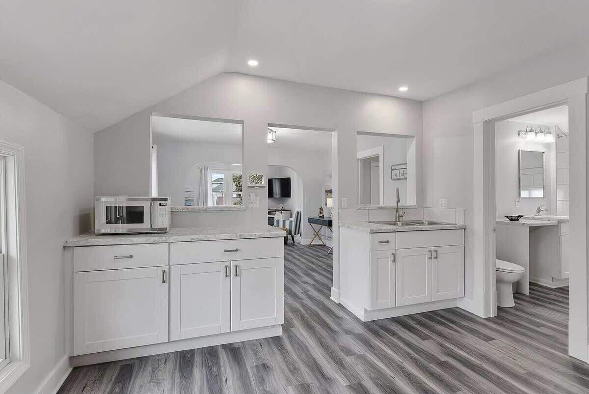A modern kitchen with white cabinets, a microwave, and a dining area in the background.