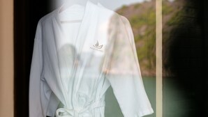 A white bathrobe with a logo hanging on a window. - Mila Lux Cruise  (Tuan Chau)