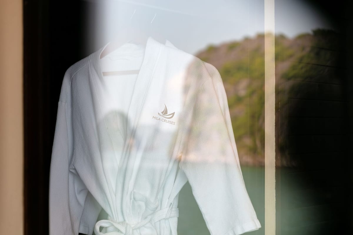 A white bathrobe with a logo hanging on a window.