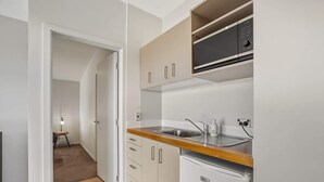 A compact kitchen with a sink, a microwave, and a refrigerator. - Studio on Martin Lane (Wānaka)