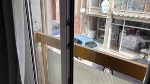 Ein Balkon mit Metallgeländer, Blick auf die Straße und ein Gebäude mit der Aufschrift "TETRA".