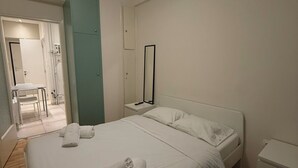 Ein Hotelzimmer mit einem großen Bett, einem Nachttisch, einem Spiegel und einem kleinen Beistelltisch.