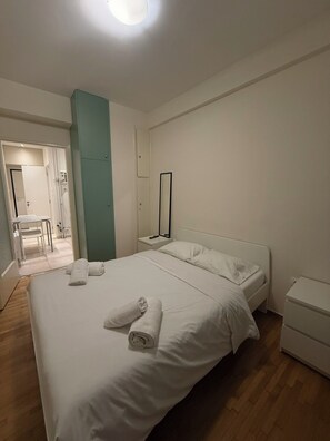 A hotel room with a large bed, a bedside table, a mirror, and a small bedside cabinet. - Urban Nook Ampelokipoi 1BR, Wifi Apt (Athens)