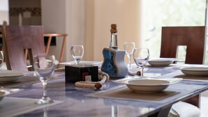 A dining table set with white plates, wine glasses, and a decorative bottle. - Vacaciones Seguras - Private Set (Ambato)