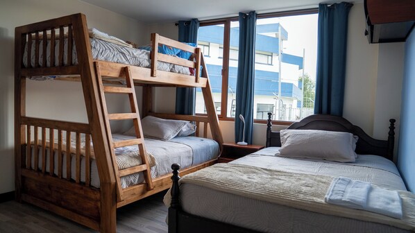 A bunk bed room with a ladder, a single bed, and a window with curtains. - Safe Vacations - Private Group (Ambato)