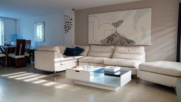 A modern living room with a beige sofa set, a glass coffee table, and a large abstract painting on the wall. - Vacaciones Seguras - Private Set (Ambato)