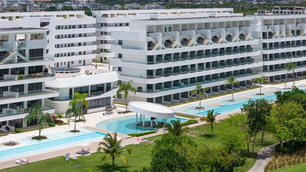 Un hôtel moderne à plusieurs étages, doté d’une piscine centrale et offrant une vue sur l’océan.
