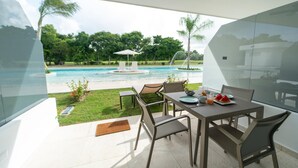 Une terrasse avec une table dressée pour deux personnes, donnant sur une piscine et une végétation luxuriante.