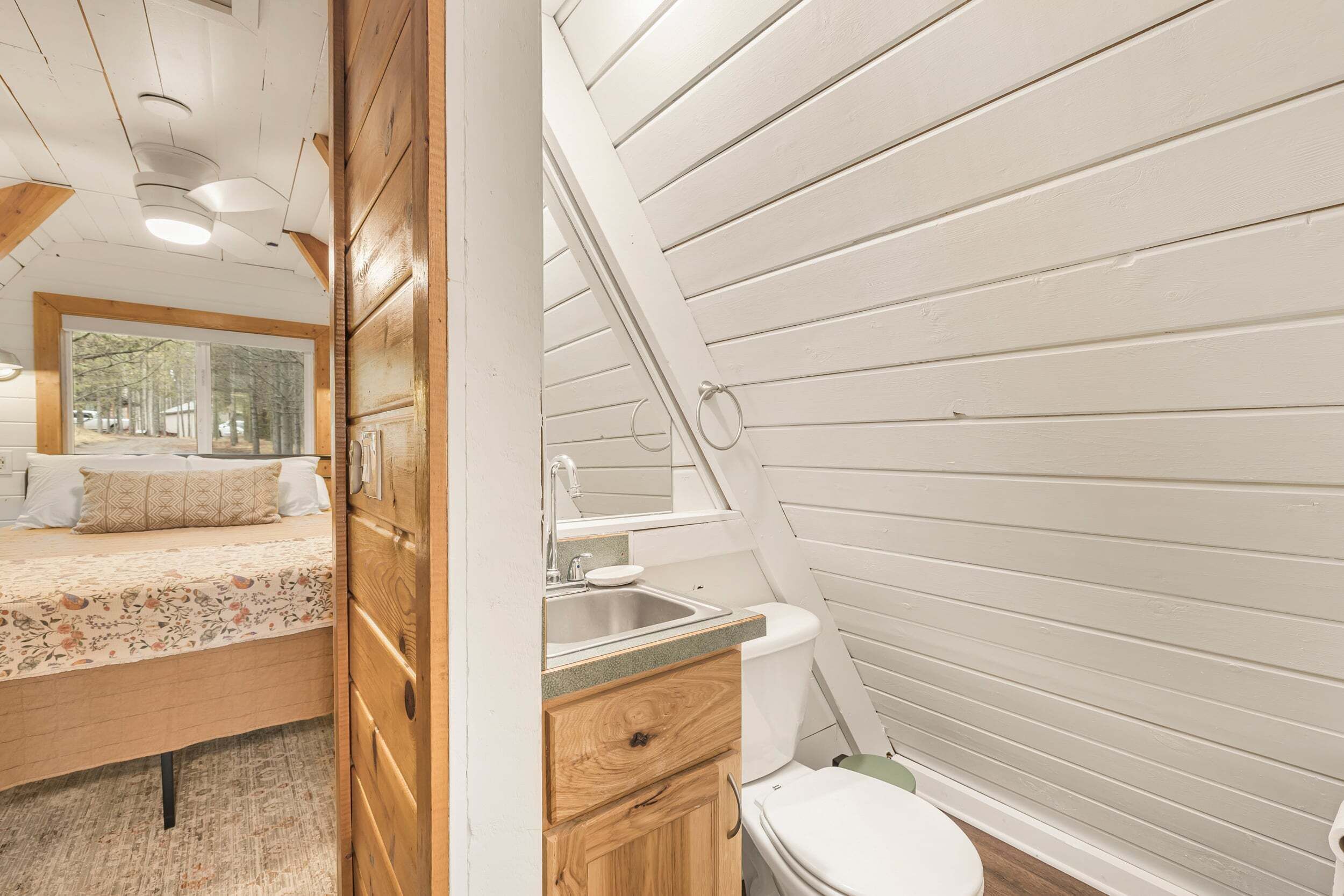 Une chambre à coucher avec un lit, une fenêtre et une salle de bain comprenant un lavabo et des toilettes.