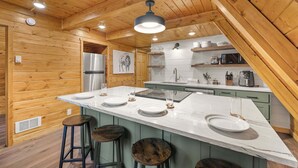 A kitchen with wooden walls, a large island with stools, a refrigerator, and a microwave. - LAKESIDE DOCKSIDE: Henrys Fork Private Beach Dock Fishing Yellowstone UTV Snowmobile Trails (Island Park)