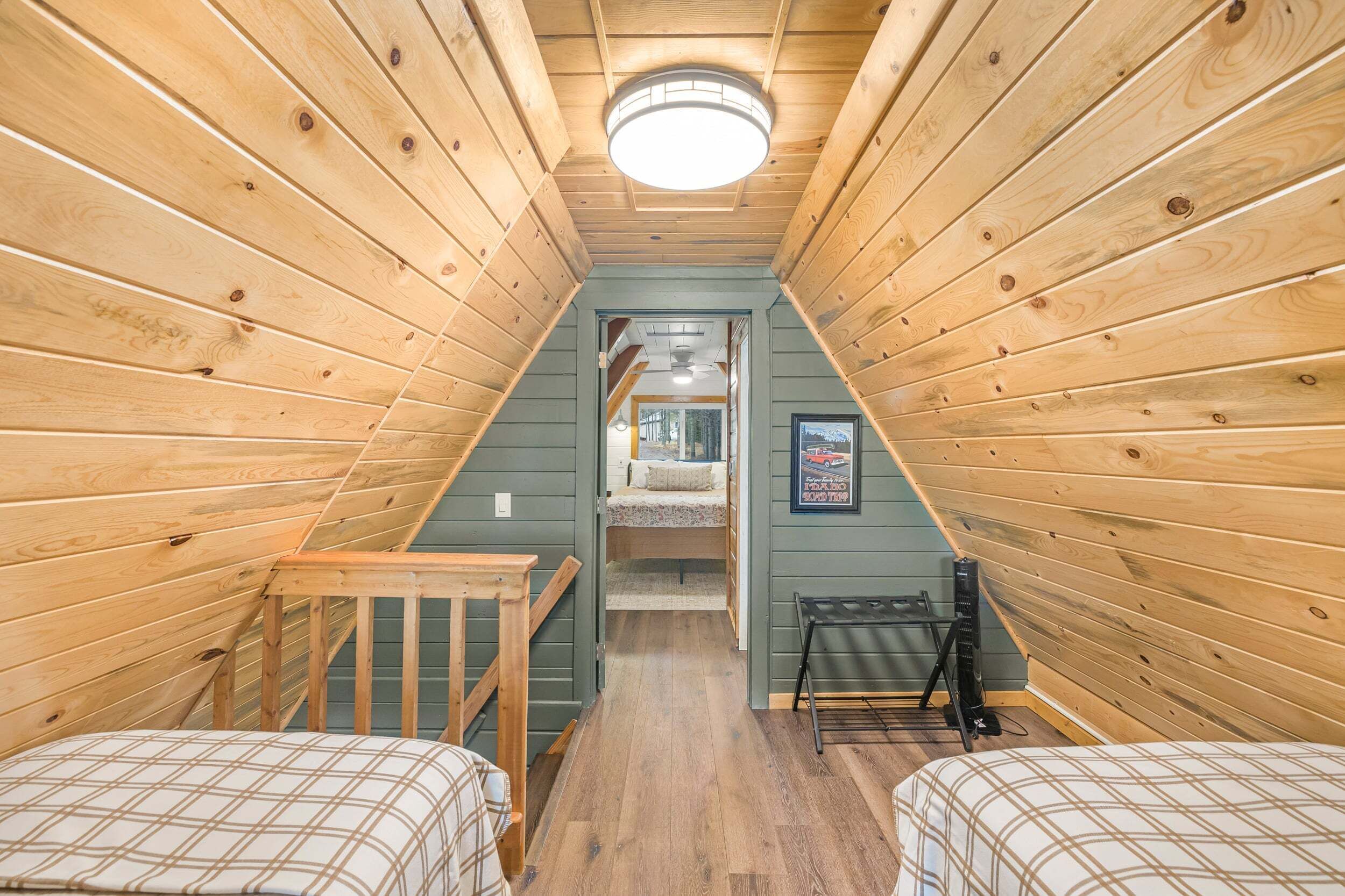 Un dormitorio estrecho en el ático con paredes de madera, techo inclinado y una cama pequeña.