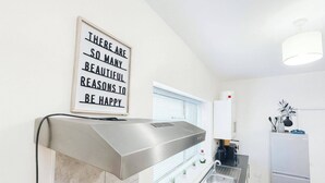 Una cocina moderna con un extractor de acero inoxidable, un lavamanos empotrado y una lámpara sobre la encimera.