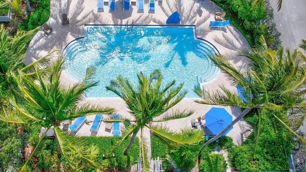 An aerial view of a resort with a central swimming pool surrounded by palm trees and sun loungers. - The Point at Coral Lagoon, Rare End of Canal Villa (Marathon)