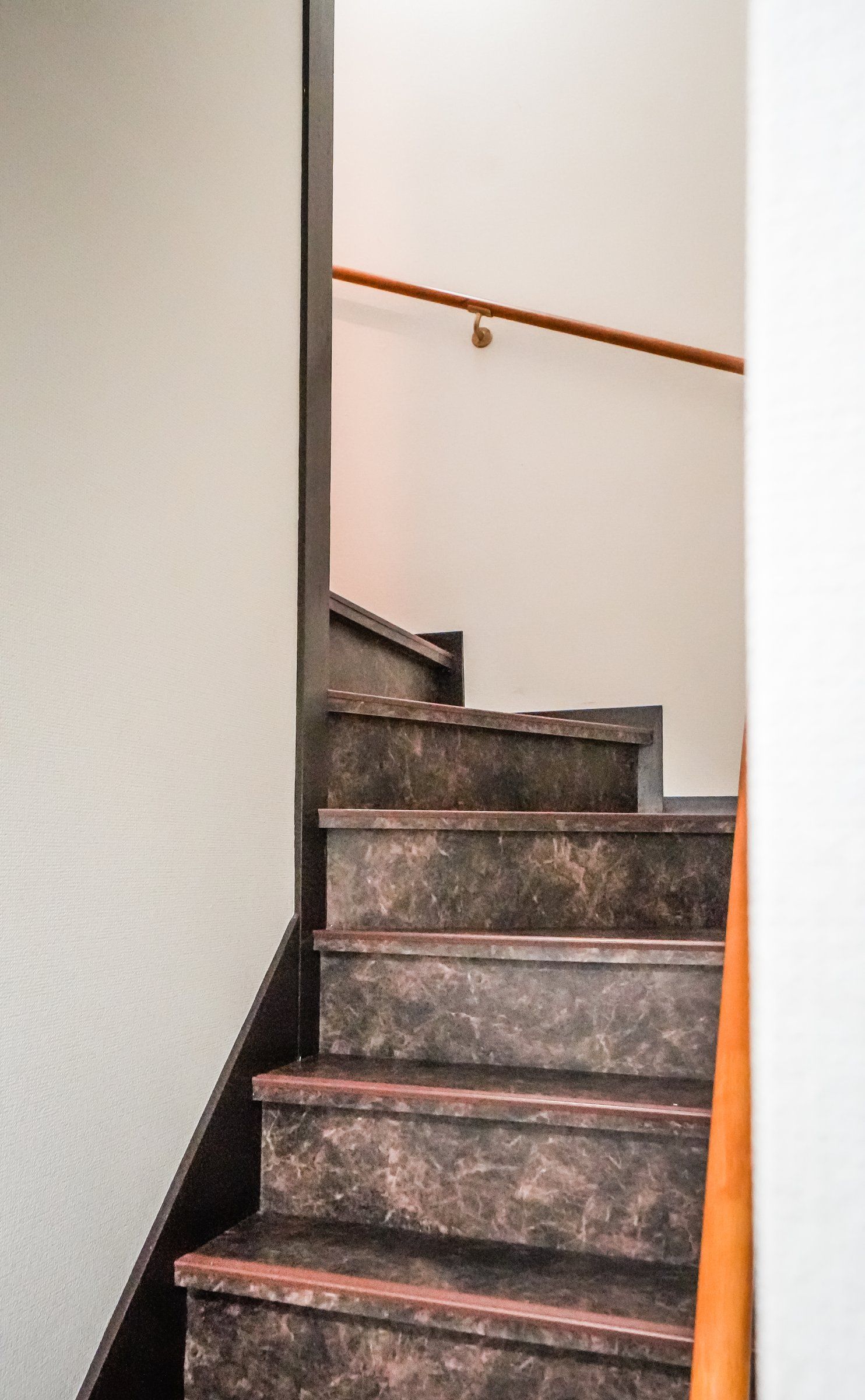A staircase with dark marble steps and a wooden handrail.