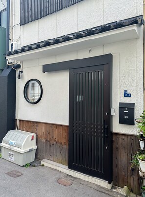 A residential building with a black gate, a mail box, and a trash bin. - meisei nihonya (Osaka)