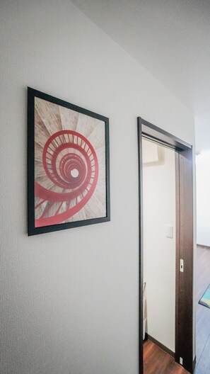 A hallway with a framed artwork on the wall and a door leading to another room. - meisei nihonya (Osaka)