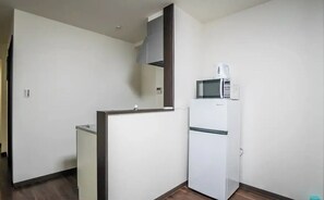 A small, compact kitchen with a microwave and a refrigerator. - meisei nihonya (Osaka)