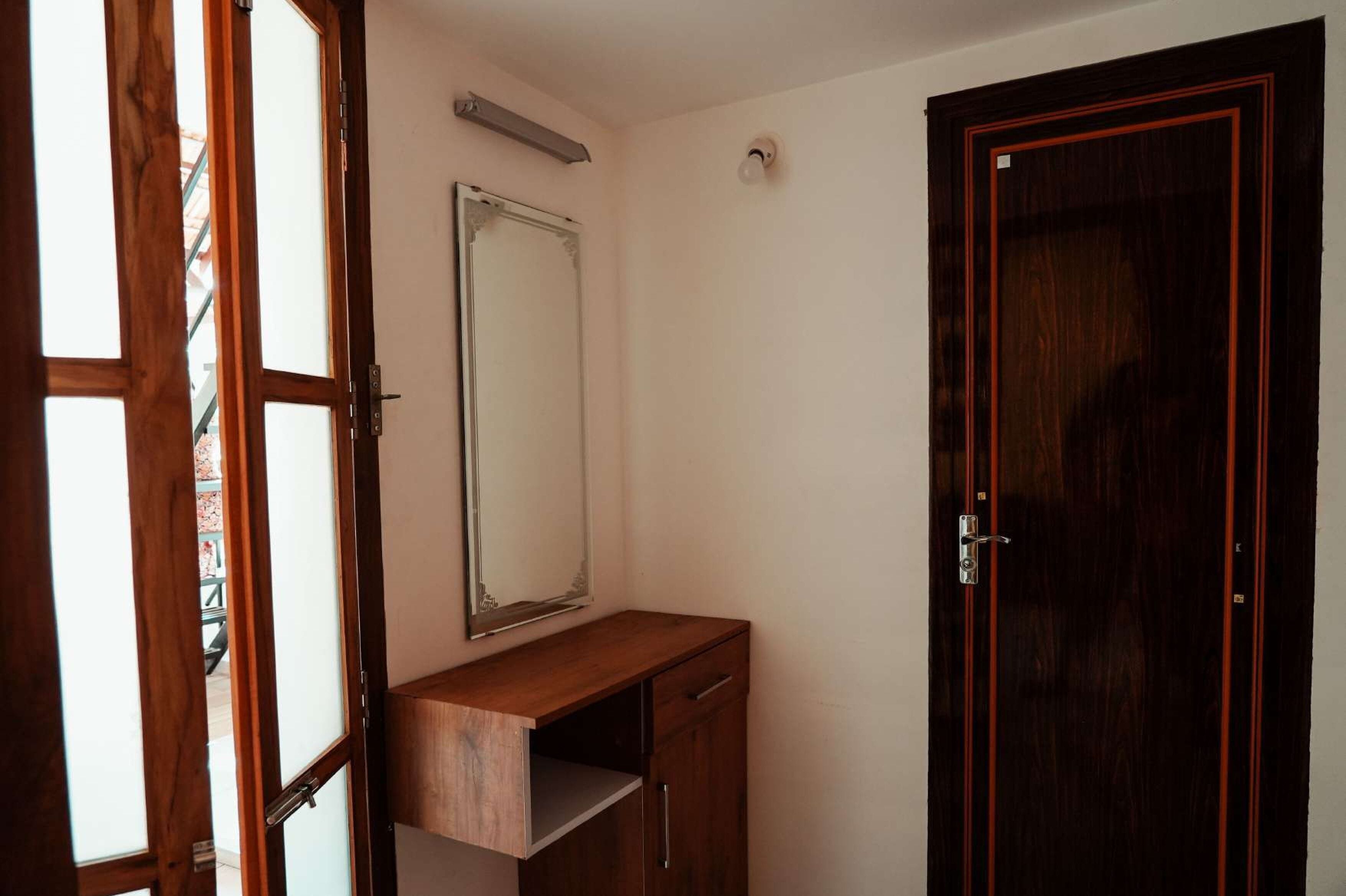 Una habitación con un escritorio de madera, un espejo y una puerta de madera oscura.