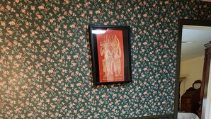 Ein Badezimmer mit einer freistehenden Badewanne, floralem Wandpapier und einem gerahmten Kunstwerk darüber.
