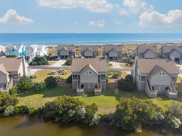 Una zona residenziale sul lungomare, con numerose case e una vista aperta sull'oceano, oltre a una piccola distesa d'acqua in primo piano.