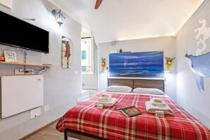 Ein Hotelzimmer mit einem Bett, einem Flachbildfernseher, einem Gemälde mit einem Segelboot und einer Wandkarte.