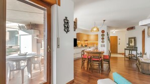 A modern kitchen with white cabinets, a wooden dining table, and a chandelier.