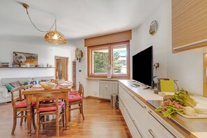 A modern kitchen with wooden furniture, a dining table, and a large window.