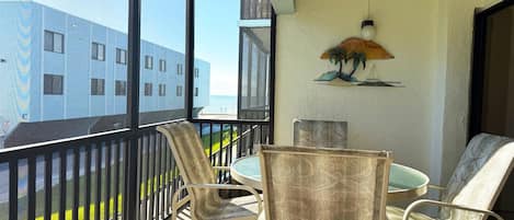 A balcony with a view of a building and a palm tree mural.