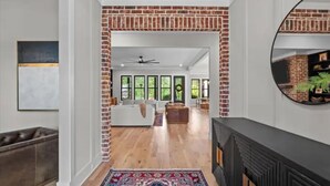 Un salon spacieux avec une cheminée en briques, un grand miroir et une vue sur la salle à manger.