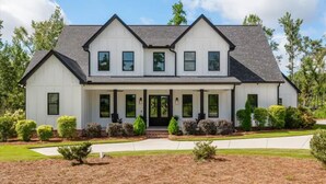 Une maison à deux étages avec un porche à l’avant, de nombreuses fenêtres et une pelouse bien entretenue.