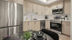 Una cucina moderna con elettrodomestici in acciaio inossidabile, mobili in legno chiaro e un'area pranzo con tavolo apparecchiato per due.