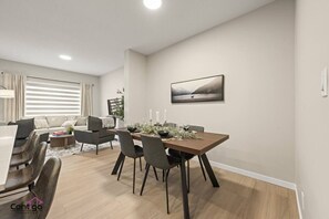 Ein modernes Wohnzimmer mit Essbereich, ausgestattet mit einer Couch, einem Couchtisch und einem Esstisch für vier Personen.