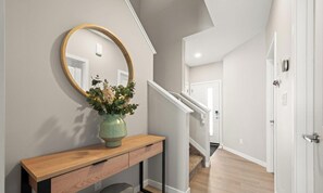 Un couloir avec une console en bois, un miroir et un vase rempli de fleurs.
