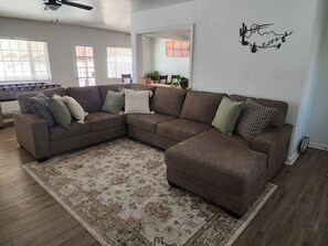 A living room with a sectional sofa, a patterned rug, and a wall art piece. - Your Desert Getaway in Sunny Yuma, AZ (Yuma)