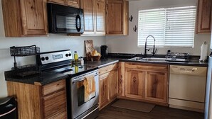 Une cuisine avec des meubles en bois, un four à micro-ondes, une cuisinière, un évier et un réfrigérateur.