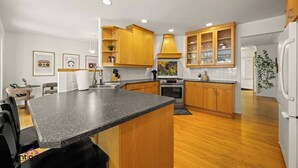 Een moderne keuken met houten kastjes, granieten werkbladen en een centraal eiland.