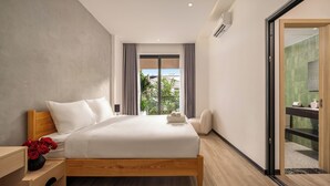 Una habitación de hotel moderna con una cama de madera, una mesita de noche con un jarrón de rosas rojas, vistas al exterior a través de un ventanal amplio y un baño visible a través de una puerta abierta.