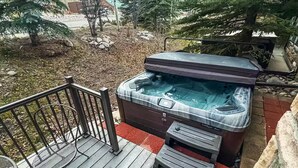 A hot tub on a wooden deck with a metal railing and a chair. - The Grand Red Quill.  3-bedroom house in Winter Park (Winter Park)