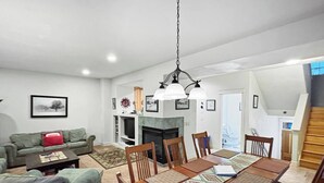 A spacious living room with a fireplace, a dining area with a wooden table and chairs, and a staircase leading to an upper level. - The Grand Red Quill.  3-bedroom house in Winter Park (Winter Park)
