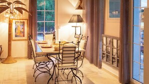 A dining area with a wooden ceiling, a table with chairs, a lamp, and a window with curtains. - Villa with Independent Studio, Pool, Jacuzzi, Playground, Quiet Nature (CHATEAUVERT)