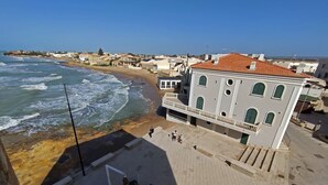 Ein Küstengebäude mit einer Terrasse mit Blick auf Strand und Meer.