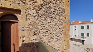 Ein Steinhaus mit einer Holztür und einem Balkon mit Blick auf eine Straße.