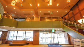 A hotel lobby with a staircase, a seating area, and a view of the street outside.