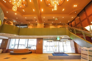 A hotel lobby with a staircase, a seating area, and a view of the street outside.
